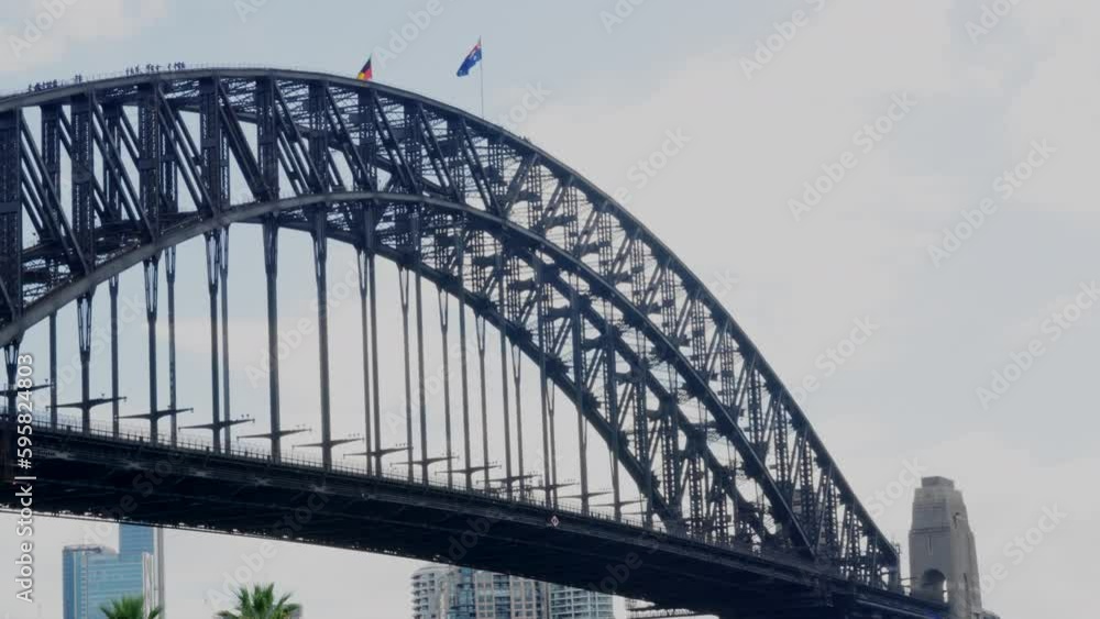 Tourists climbing over Sydney Harbour Bridge as the Aboriginal and Australian flags fly overhead, in Australia Tourists climbing over Sydney Harbour Bridge as the Aboriginal and Australian flags fly overhead, in Australia