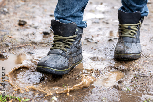 A man in jeans and boots walks through the swamp in rainy weather. © puhimec
