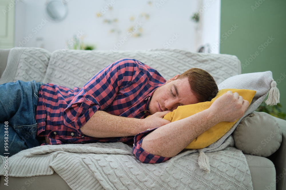 man soundly sleeping on a comfortable couch in his home, wearing headphones and likely listening to music or engaging in meditation. soft lighting and serene colors.