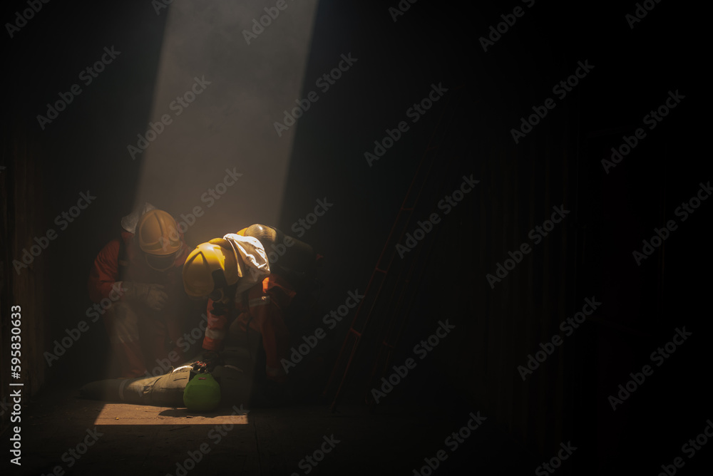 Two firefighters are working together to simulate a rescue scenario with the dummy models in the dark room with soft light. Two firefighters are working together to simulate a rescue scenario with the dummy models in the dark room with soft light.