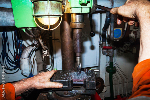 Drilling a steel plate clamped in a vice on a drilling machine.