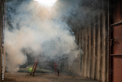 Ladder is covered in smoke and there is a dummy of a victim lying in the galvanized room with soft light.