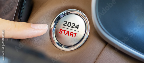 Finger press a car ignition button with 2024 START text inside  automobile. New Year New You, forecast, resolution, motivation, change, goal, vision, innovation and planning concept