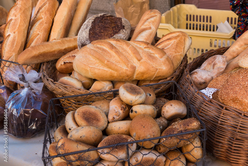Different types of fresh bread for sale on the table in an outdoor market.