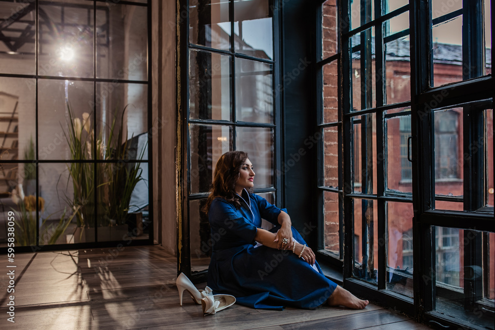 Obraz premium Beautiful brunette sitting barefoot by the window in the loft