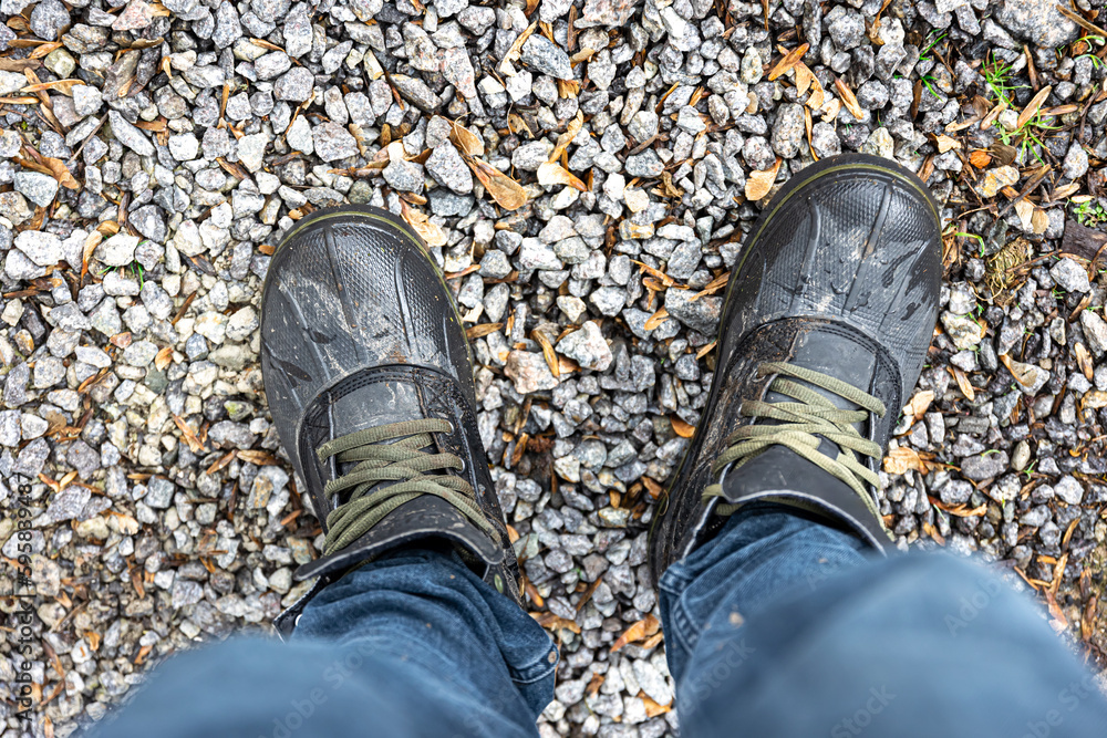 A man in boots stands on gravel, top view.