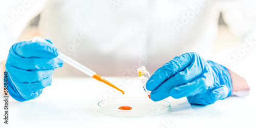 a scientist examines a chemical sample on a peri dish in a laboratory. banner with copy space