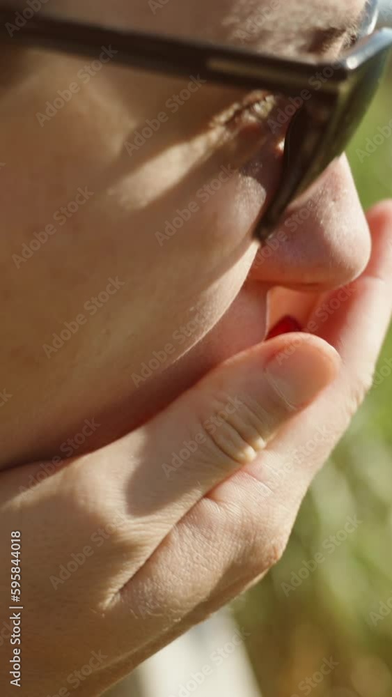 The young woman cleans pomegranate seeds and eats them from the palm of her hand. on the background of the sea, close-up Vertical video Social Media The young woman cleans pomegranate seeds and eats them from the palm of her hand. on the background of the sea, close-up Vertical video Social Media