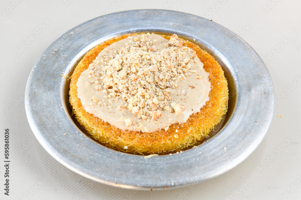 Pistachio kadayif on a plate. Turkish Dessert Kadayif with pistachio powder. Kunefe. Local name burma kadayif Pistachio kadayif on a plate. Turkish Dessert Kadayif with pistachio powder. Kunefe. Local name burma kadayif