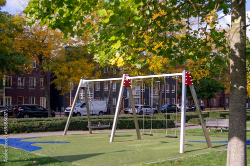 Suspended modern swing on the playground. Soft lawn covering