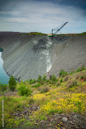 Backfilling of the spent iron ore quarry with a walking excavator in the evening