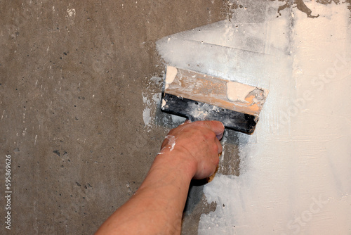 putty. Man plastering wall with putty knife indoors, closeup. home renovation