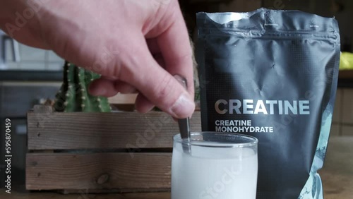 Close up of a hand mixing creatine monohydrate in a glass 4K slow motion photo