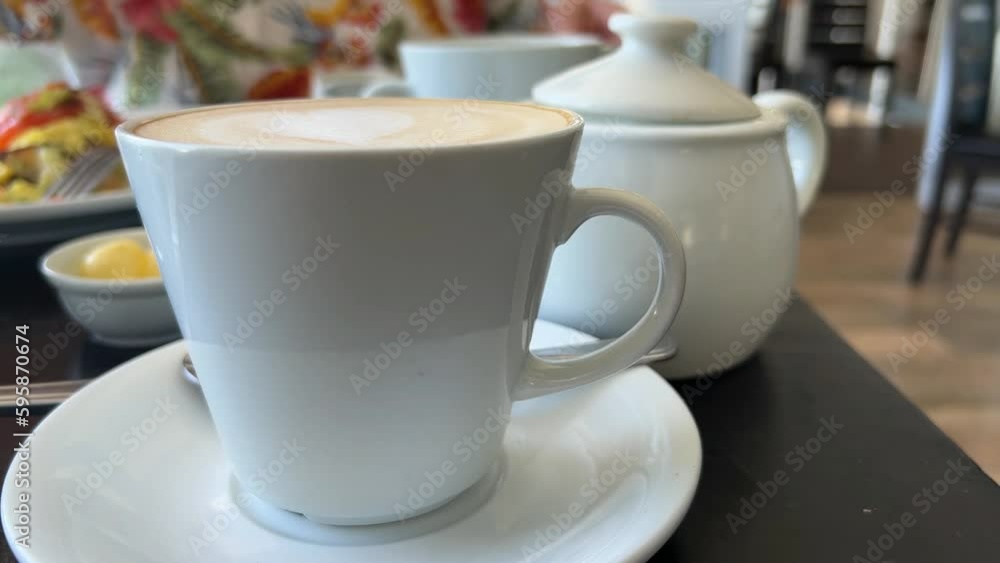 A cup of coffee and milk jug on a table A cup of coffee and milk jug on a table