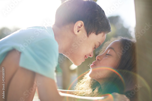 Close up sister kissing cute brother with Down Syndrome in sunshine photo