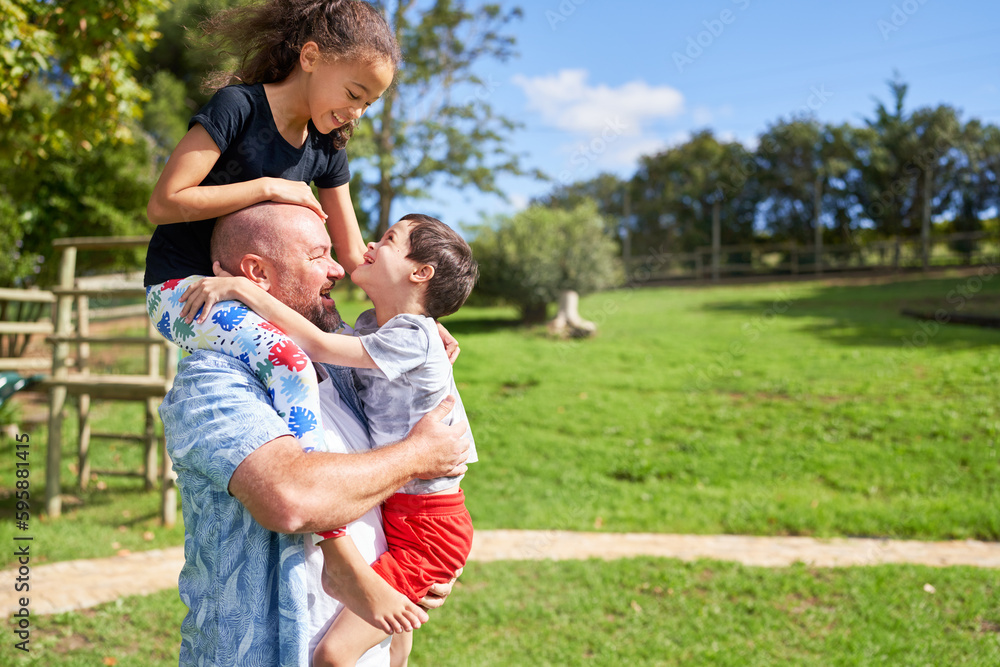 Father holding cute, playful kids in sunny summer park Father holding cute, playful kids in sunny summer park