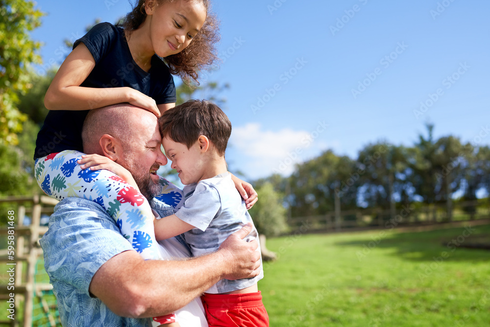 Father holding, carrying daughter and son with Down Syndrome in park Father holding, carrying daughter and son with Down Syndrome in park