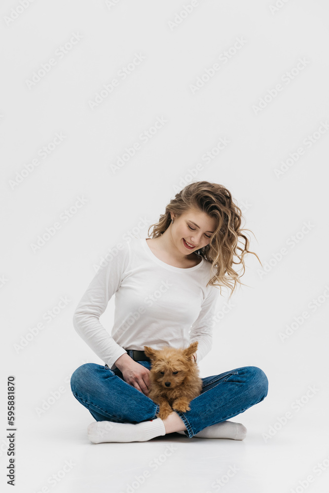 Happy woman lies on the floor with her dog. Charming dog sniffs something in front of him, lying on the lap of the girl. Young woman holding her curious puppy Happy woman lies on the floor with her dog. Charming dog sniffs something in front of him, lying on the lap of the girl. Young woman holding her curious puppy