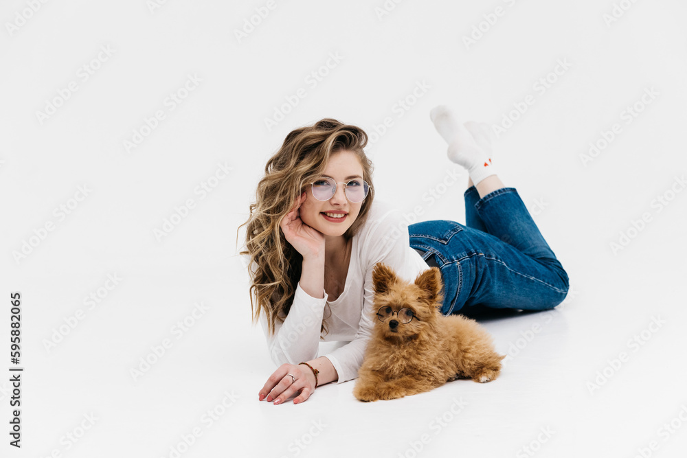 A cute young woman kisses and hugs her puppy. Love between owner and dog. Isolated on white background. Animal love concept A cute young woman kisses and hugs her puppy. Love between owner and dog. Isolated on white background. Animal love concept