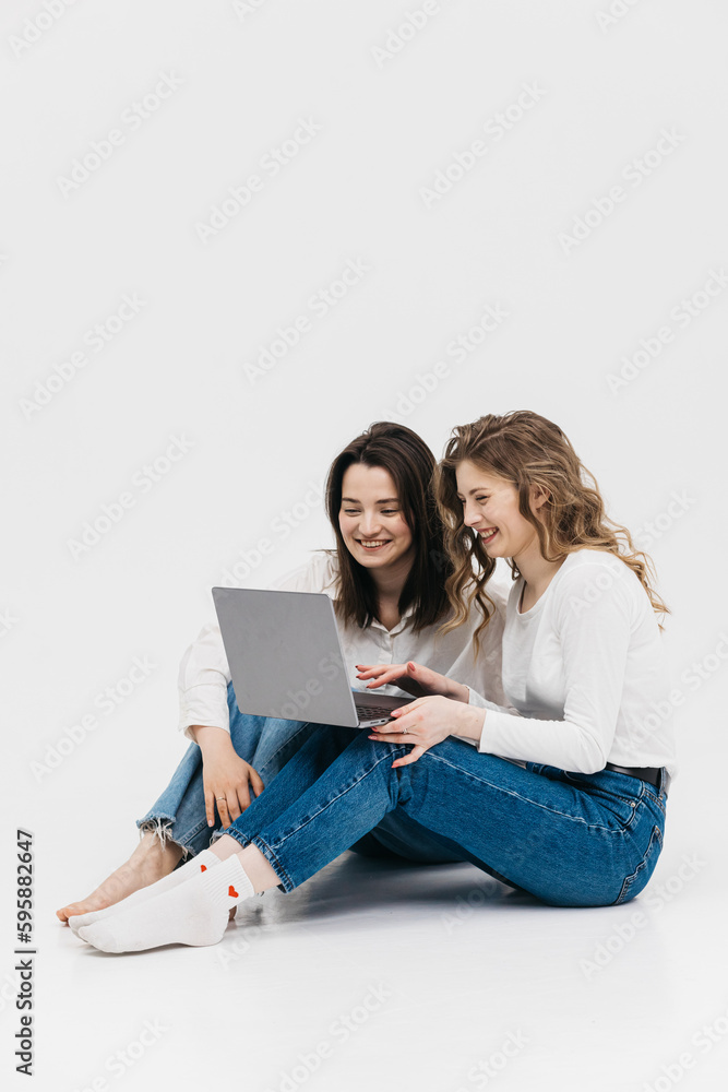 Young happy couple of young women on white background communicate showing laptop together. Chroma Key Young happy couple of young women on white background communicate showing laptop together. Chroma Key