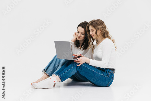 Young happy couple of young women on white background communicate showing laptop together. Chroma Key