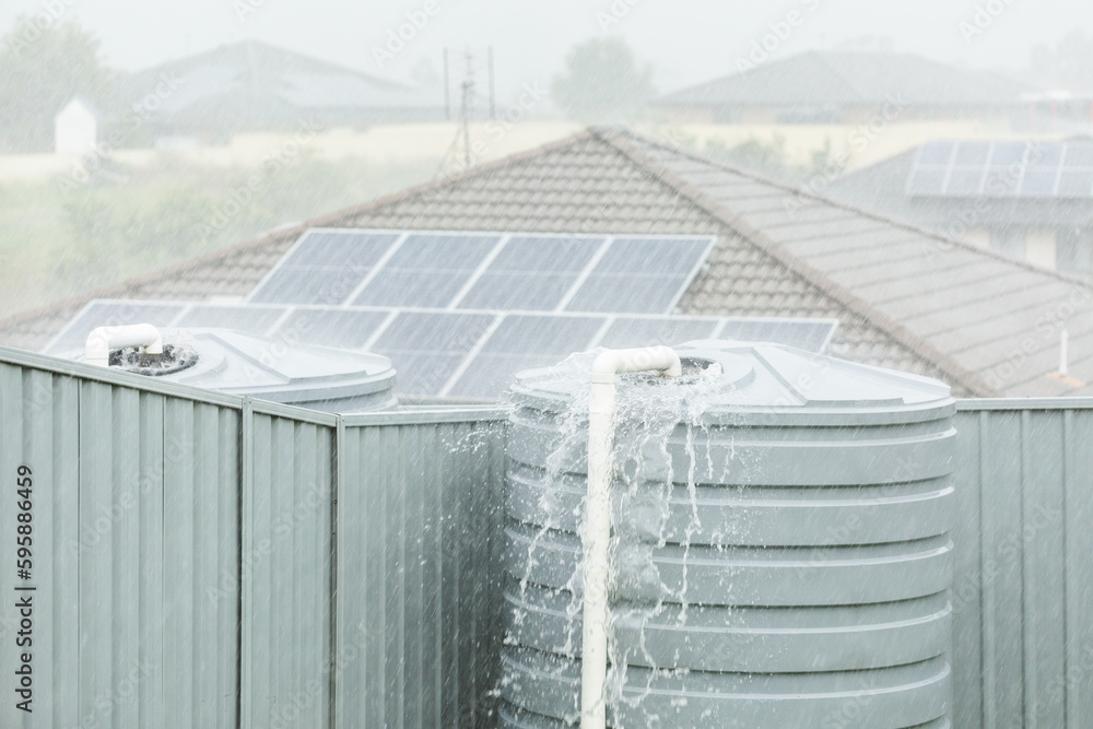 Heavy rainfall in backyard with water overflowing from tank Stock Photo
