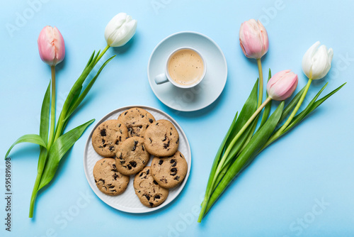 Cup of coffee mug with coffee, cookies and tulips on a colored background. Greeting spring card top view #595891698