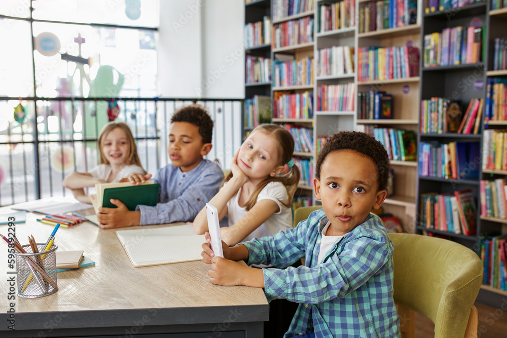 Mixed-race pupils study and write at table in library or classroom. Back to school. Mixed-race pupils study and write at table in library or classroom. Back to school.