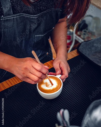 barista making coffee, the hand of a barista with a wooden spoon making or preparing coffee foam in a cup of coffee.