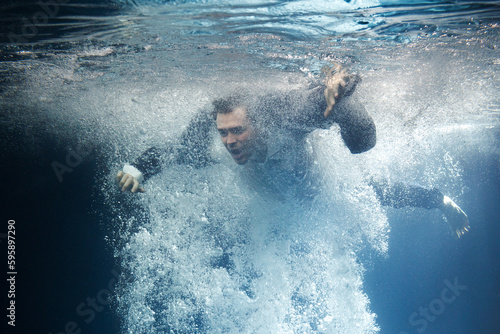 A businessman in a suit swims through the swirling current. © Artem Zakharov