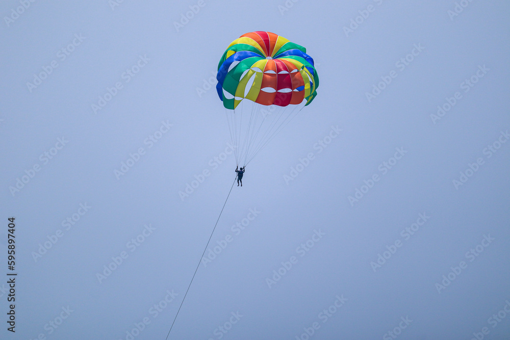 the man flying in the clear sky with parachute doing para gliding the man flying in the clear sky with parachute doing para gliding