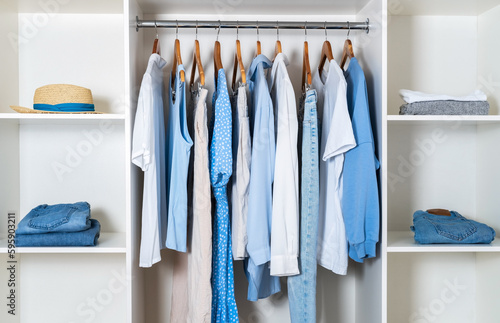 Modern white wardrobe with stylish spring and summer clothes and accessories. Organization of storage in the closet concept.