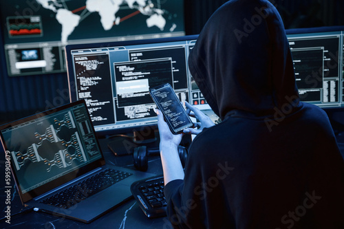 Modern technology. Young professional female hacker is indoors by computer with lot of information on displays