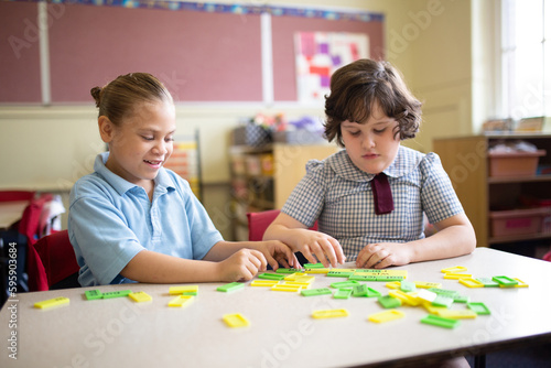 Two primary school girl students collaborating with coloured word tiles photo