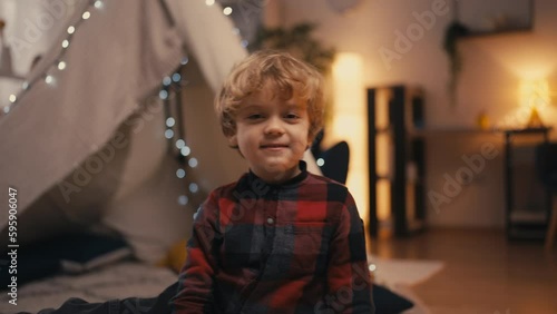Portrait of cute little boy sitting in front of blanket fort at home, innocence