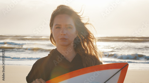 Photography Woman surfer stands with surfing board on the tropical beach