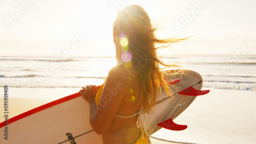 Woman surfer walks with surfing board on the tropical beach