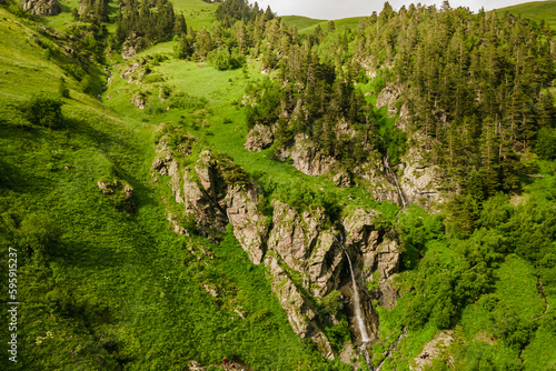 Aerial view of waterfall in green alpine mountains