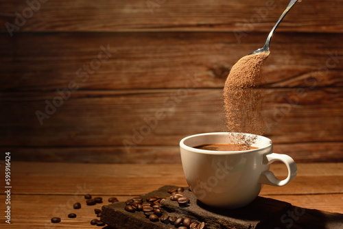 pouring coffee powder on coffee cup on brown wooden borrd background