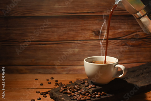 pouring hot coffee from coffee pot ,coffee beans spread on old wood floor