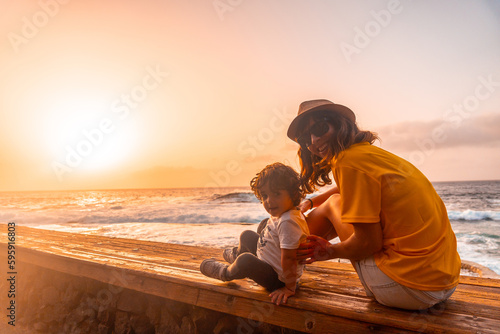 Mother and son at sunset in the natural pools of La Maceta in El Hierro, Canary Islands. Sitting looking at the sea on summer vacation © unai
