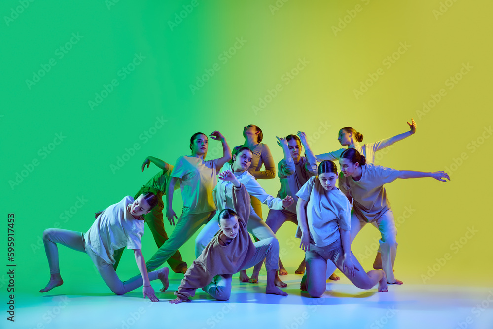 Group of young people dancing contemp against green and yellow gradient background in neon light. Diversity, chaos and freedom