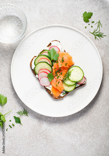 Smorrebrod, toasted bread with rye bread, salmon,curd cheese with herbs, green wild onion, cucumber and radish. Hearty and healthy Scandinavian and Baltic  snack, lunch. Summer menu
