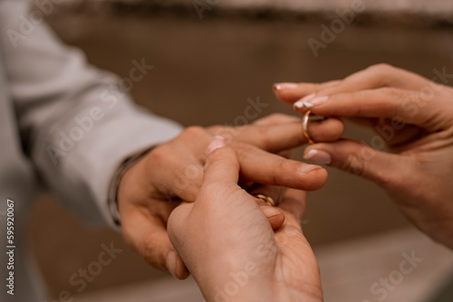 Noiva em um casamento colocando a aliança no dedo do noivo.