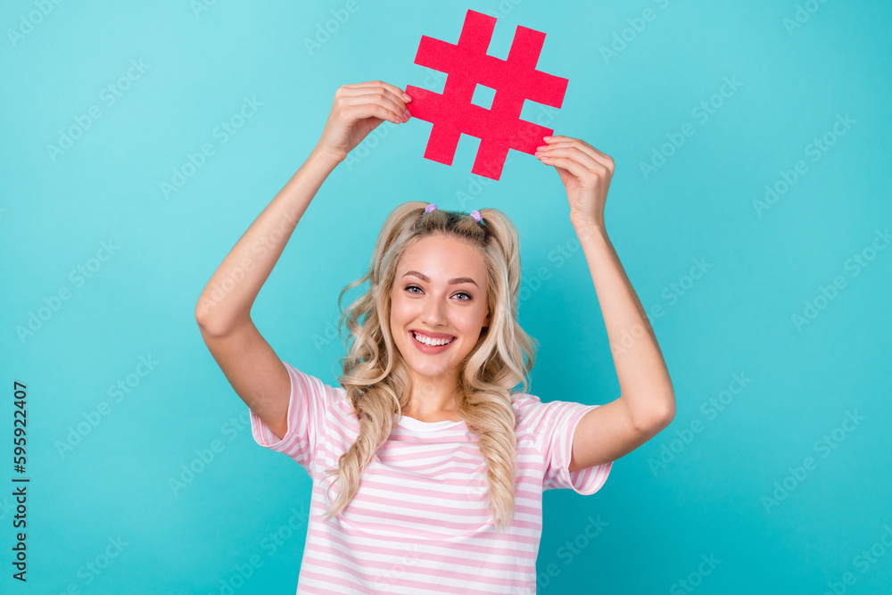 Portrait of pretty positive person arms hold paper hashtag symbol above head isolated on turquoise color background Portrait of pretty positive person arms hold paper hashtag symbol above head isolated on turquoise color background