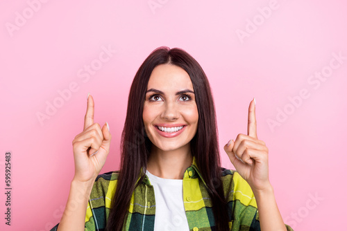 Portrait of cheerful person with long hairstyle wear plaid shirt directing at empty space proposition isolated on pink color background