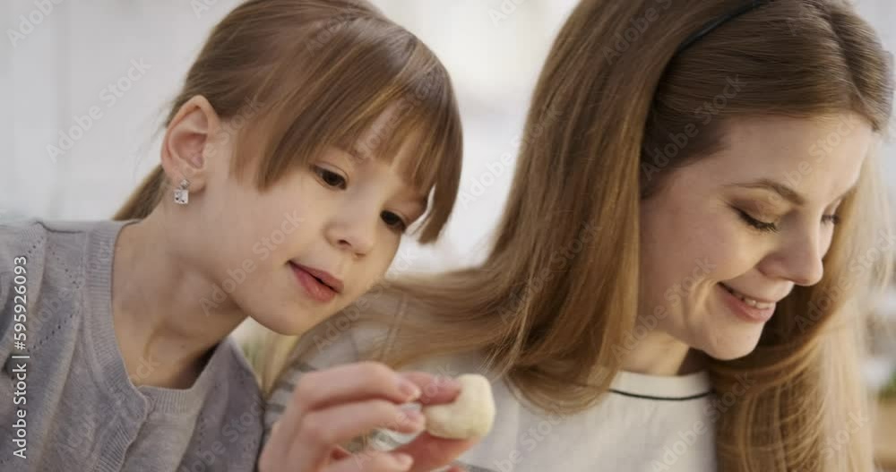 Slow motion shot of caucasian young mother showing heart shaped cookie dough to cute daughter learning to cook in kitchen Slow motion shot of caucasian young mother showing heart shaped cookie dough to cute daughter learning to cook in kitchen