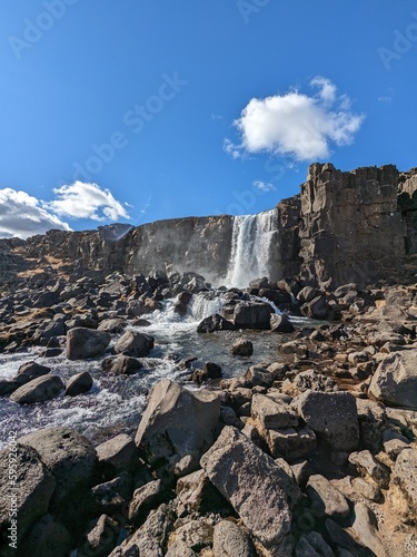 Waterfall with a blue sky in the background and rocks at the front