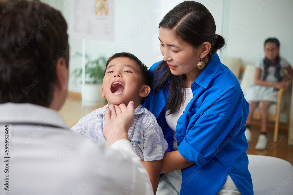 Pediatrician asking boy to open mouth wide so he could check his throat Pediatrician asking boy to open mouth wide so he could check his throat