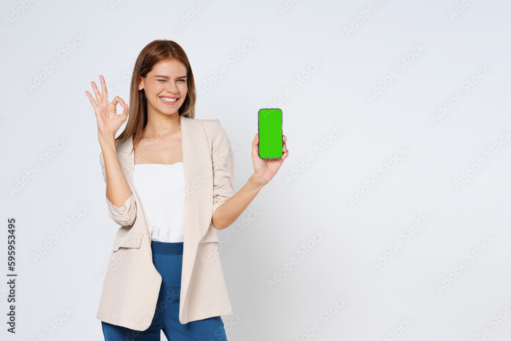 Young woman holding smartphone and shows OK sign on white background. Young woman holding smartphone and shows OK sign on white background.